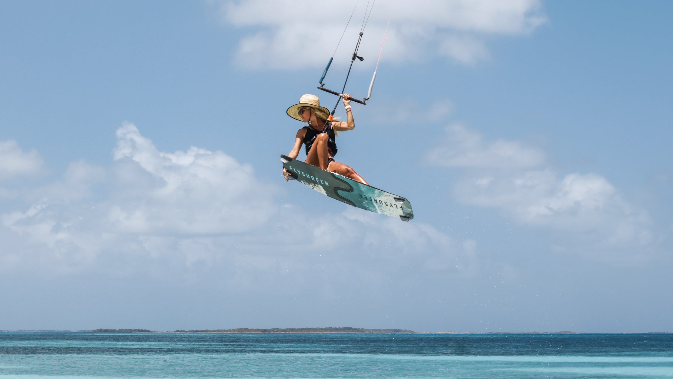 Kitesurfer s Flysurfer TRIP2 v zraku nad kristalno modrim morjem, prikaz svobode in lahkotnosti z ultralahkim kajtom.